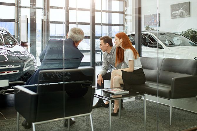 Man in dealership going over terms with couple buying car